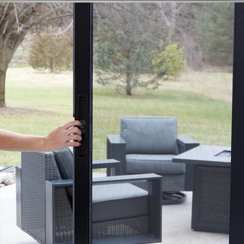 opening black framed sliding pation door out to patio area of home