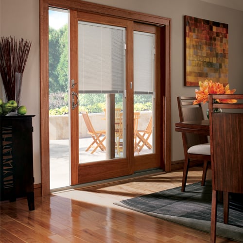Dining room with patio door with built in shades half closed. 